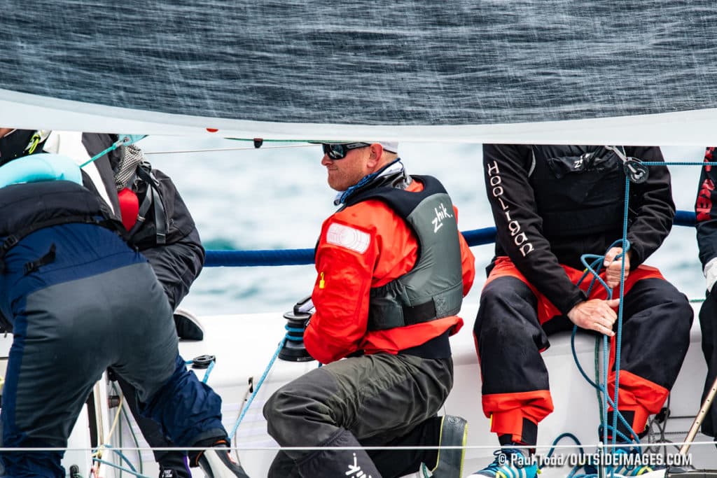 men in red vests on sailboat