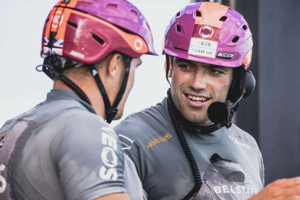 Two America's Cup sailors in uniform and helmets converse during the America's Cup 36 elimination rounds.