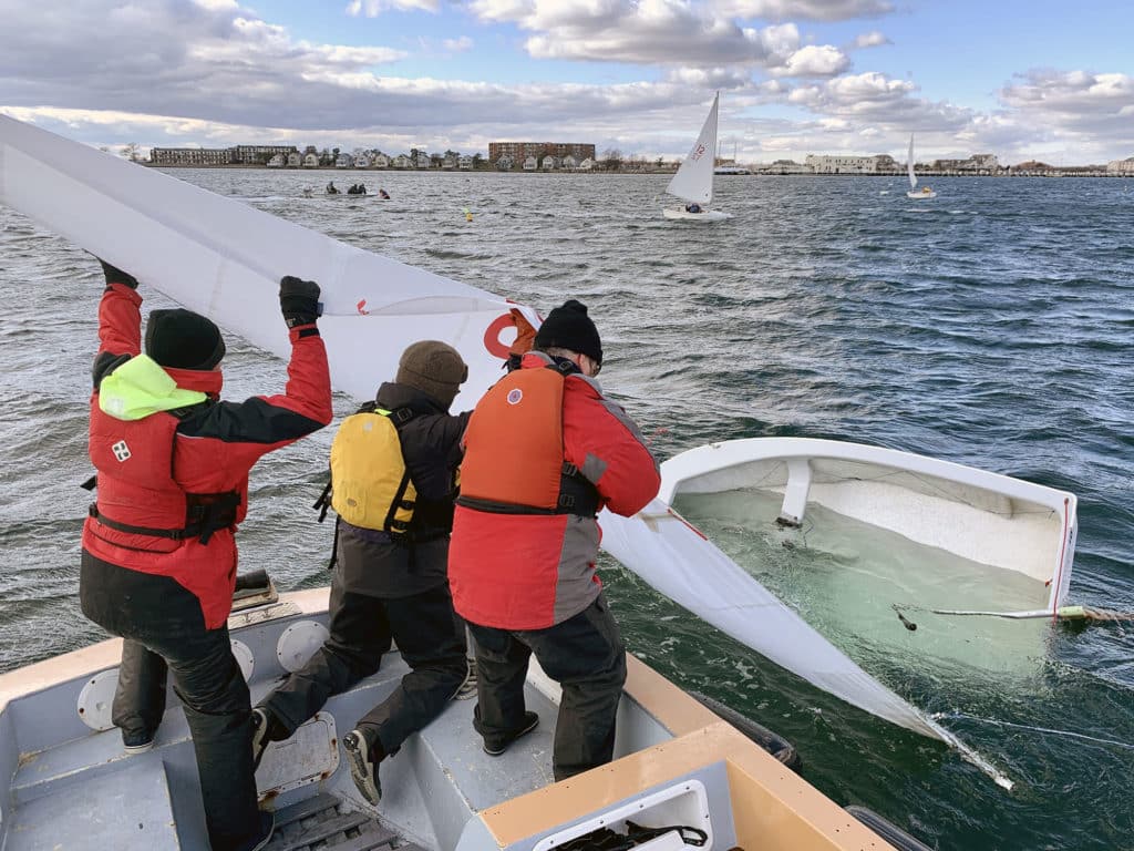 Sailors rescue a capsized and sunken sailing dinghy from a powerboat.