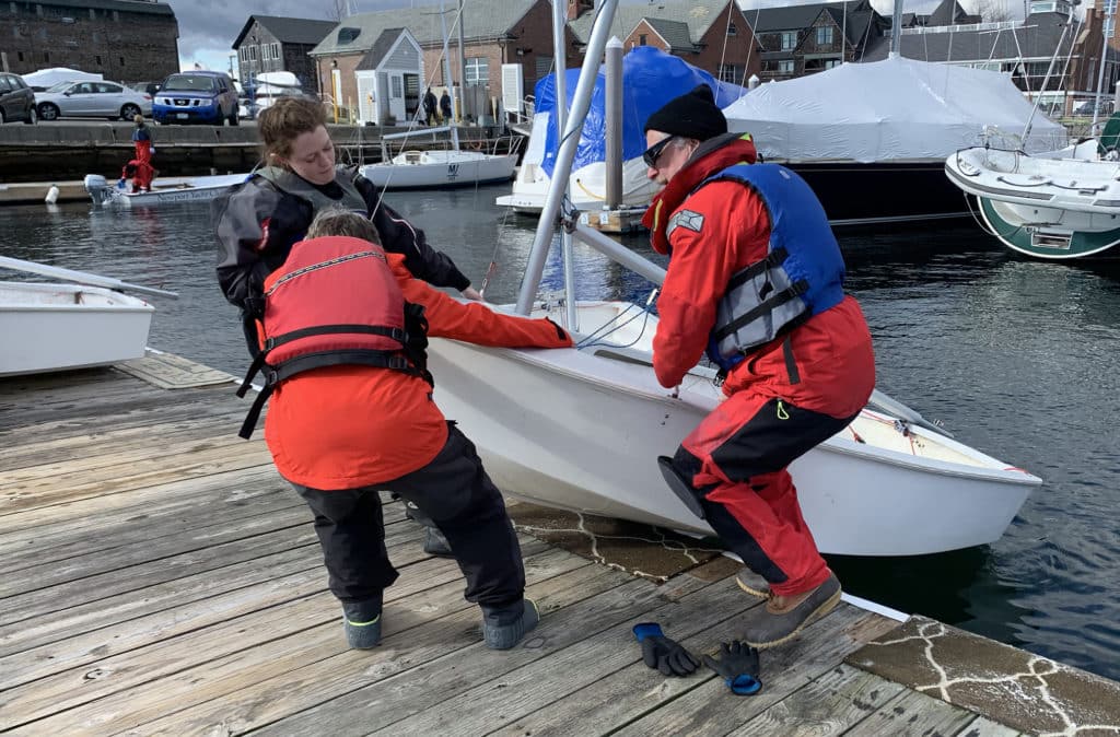 Sailboat racers pulling small dinghy up onto a dock in Newport, Rhode Island.