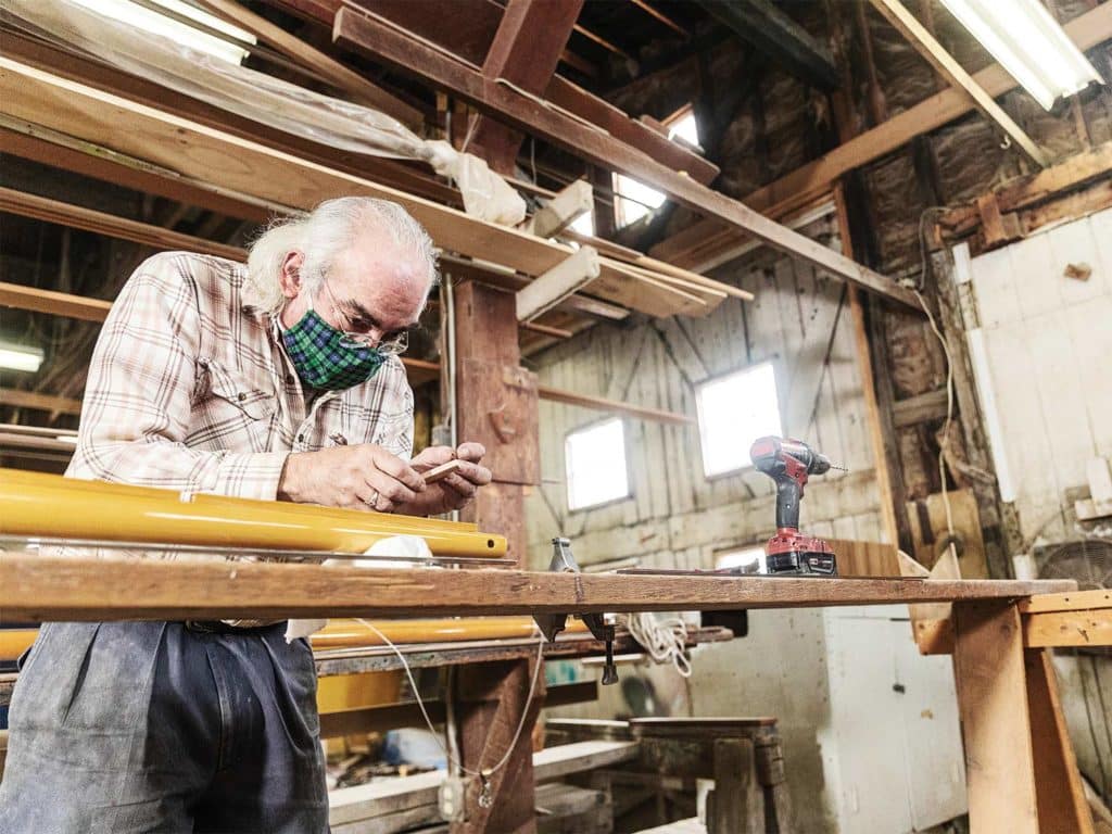 A man assembles a gaff in a carpentry shop.