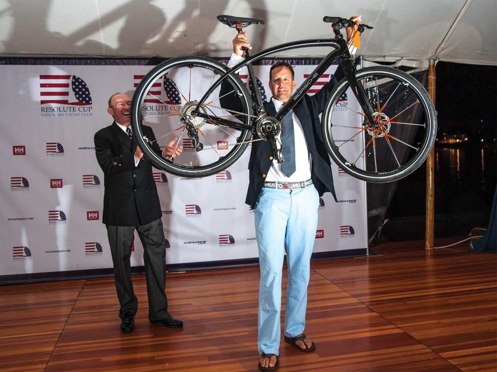 A man holding up a bike at an Awards Ceremony.