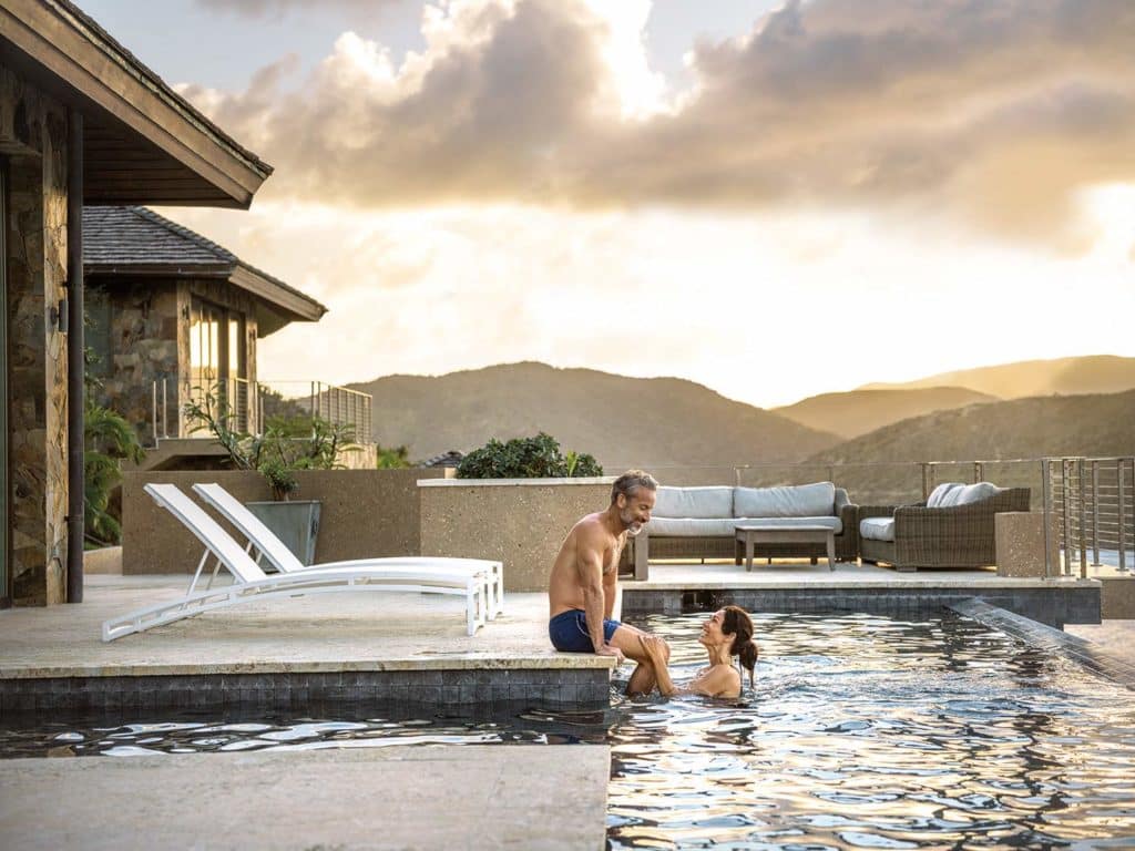 A couple relax poolside at a beach resort.