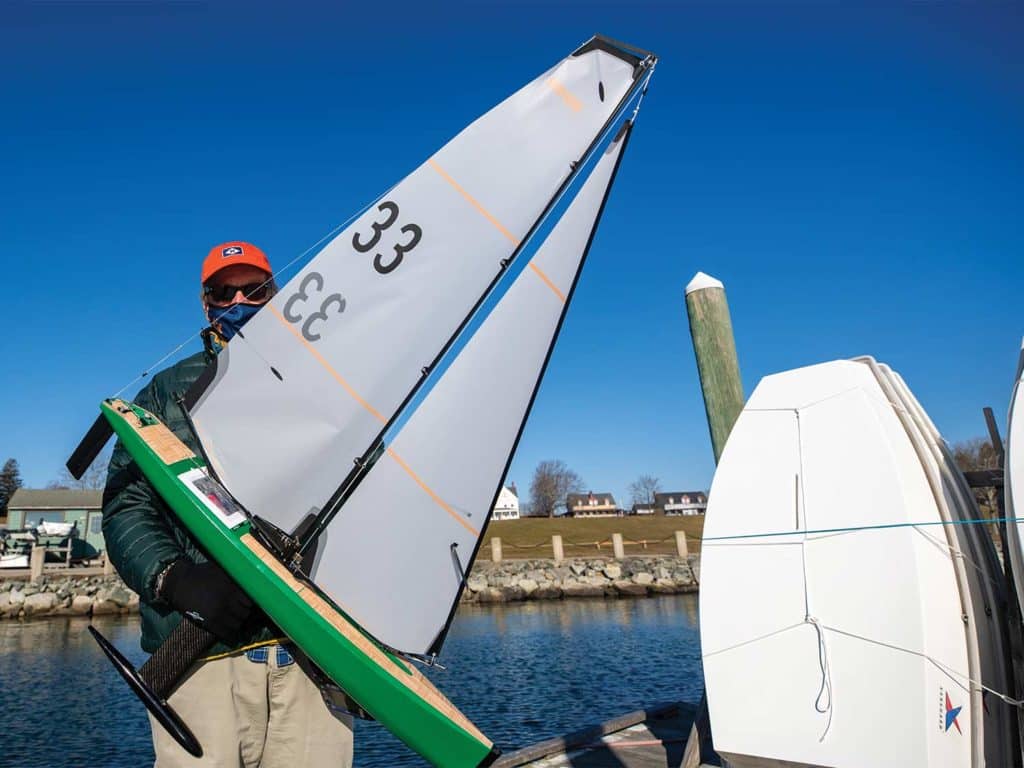 A man holds up a remote control sailboat.