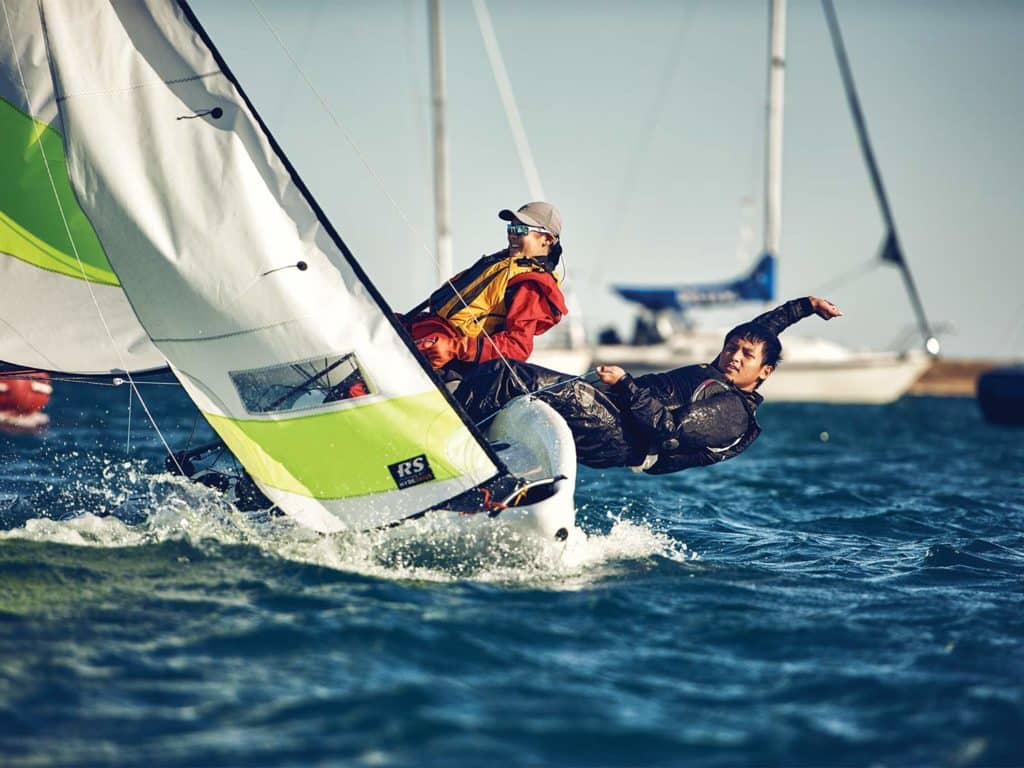 Two sailors race a boat across the water.