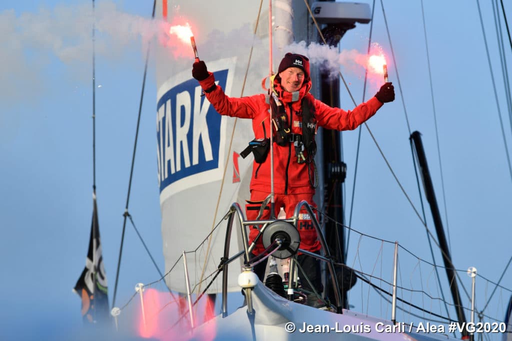 sailor finishing around the world race in France, holding flares