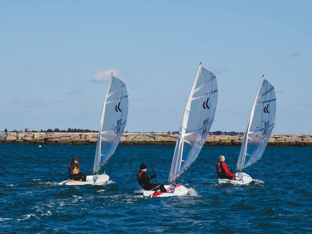 Three sailboats sailing on the open waters.