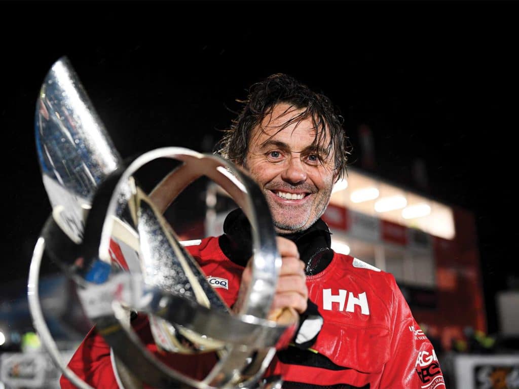 A man stands near a trophy to celebrate a sailboat race.