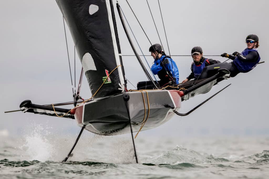 Sailors on the 69F foiling sailboat, lifted out of the water at full speed