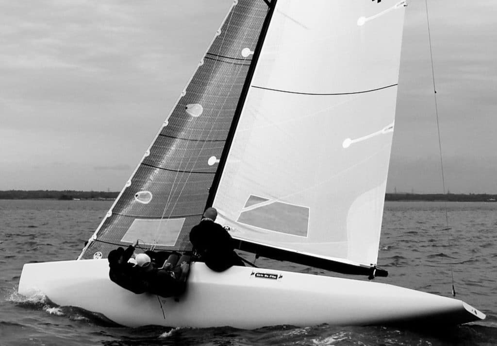 sailboat sailing upwind with crew hanging over the side