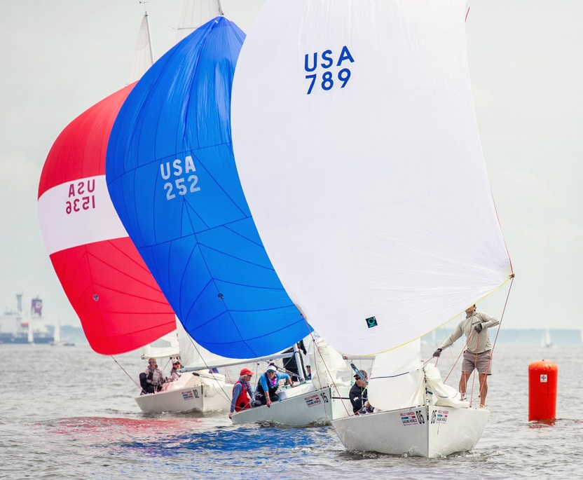 sailboats with spinnakers racing past a marker