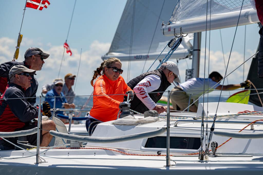 crew pulling ropes on a a racing sailboat