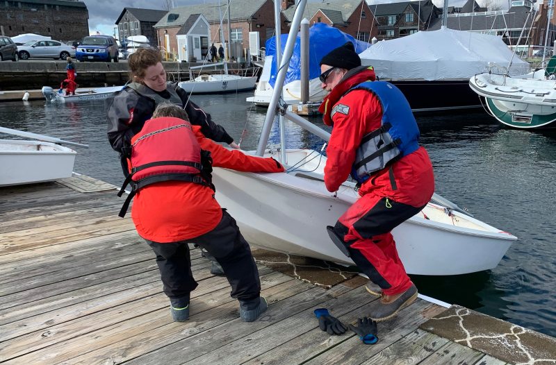 Sailboat racers pulling small dinghy up onto a dock in Newport, Rhode Island.