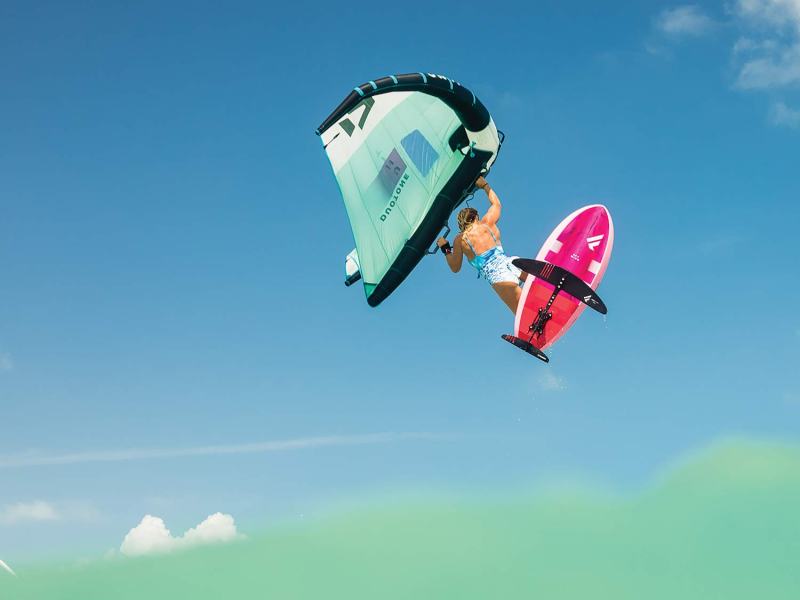 paula-novotna-freestyle-kiteboard A woman freestyle kiteboarding through the air.
