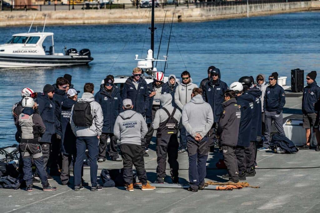 A group of sailors at the American Magic team base in Pensacola, Florida having a meeting on the dock before sailing.