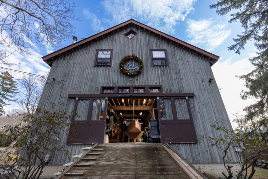 Front view of a family barn on a day with a clear blue sky. The double front barn doors are open to show the workshopo inside.