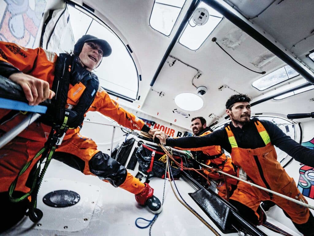 Justine Mettraux, Charlie Enright and Jack Bouttell wrestle the tiller to turn the boat down after a 52-knot puff knockdown.