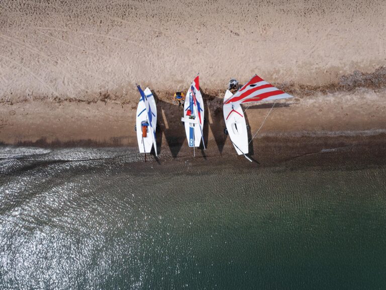 Three Sunfish sailboats onshore