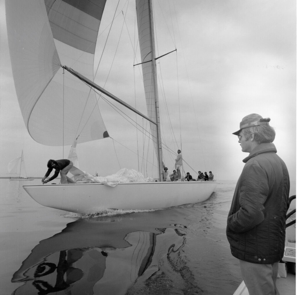 Ted Turner watches the 12 Meter Yacht Courageous sail past on the water.